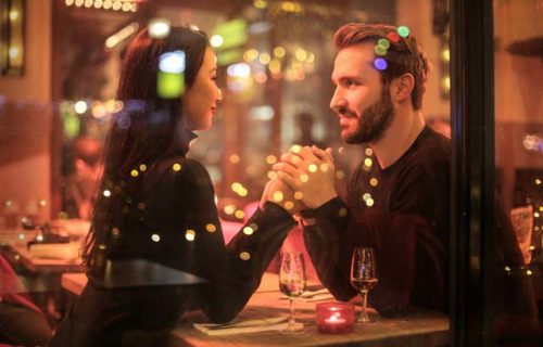 Pareja tomada de las manos sentados en un restaurante