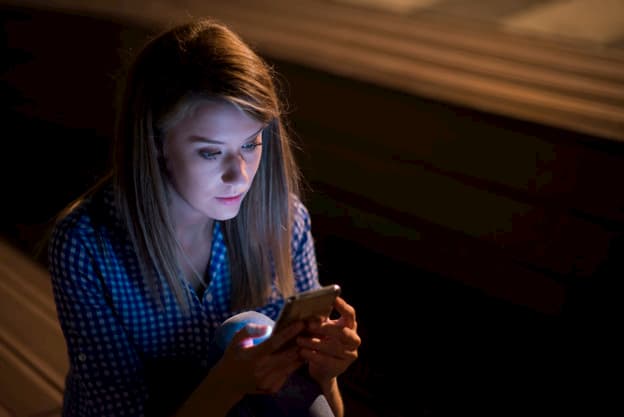 Mujer triste sosteniendo y revisando el celular