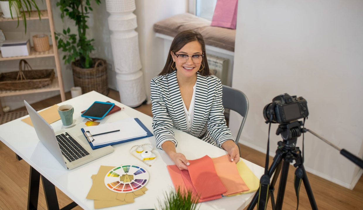 Ready for recording. Joyful nice woman sitting at the table while being ready to record the video